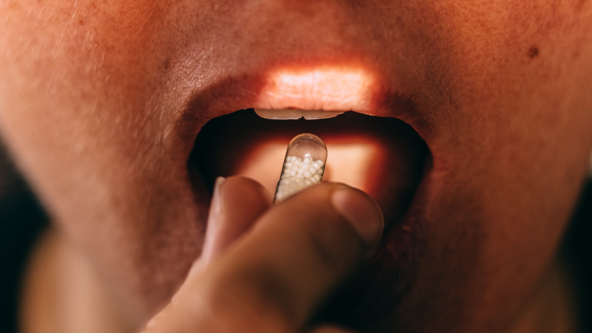 Person placing oral medicine on their tongue