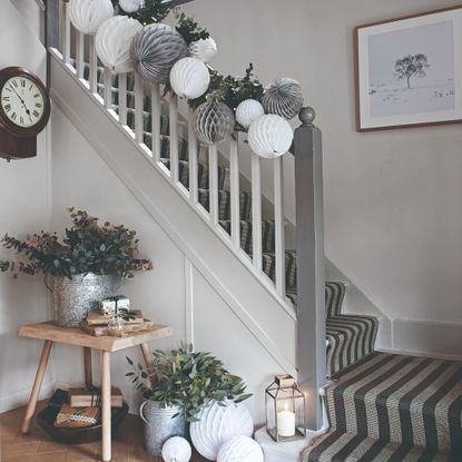 A Christmas-decorated staircase with Scandi paper decorations and a striped runner