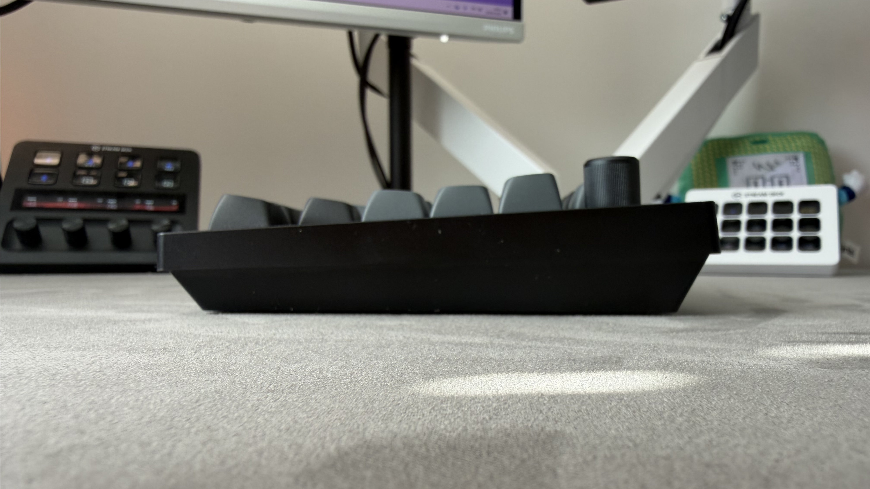 A side-on view of the Keychron V1 Ultra 8K, with a monitor and the Elgato Stream Deck visible in the background.