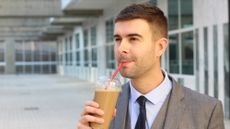 A stock photo of a man drinking iced coffee.
