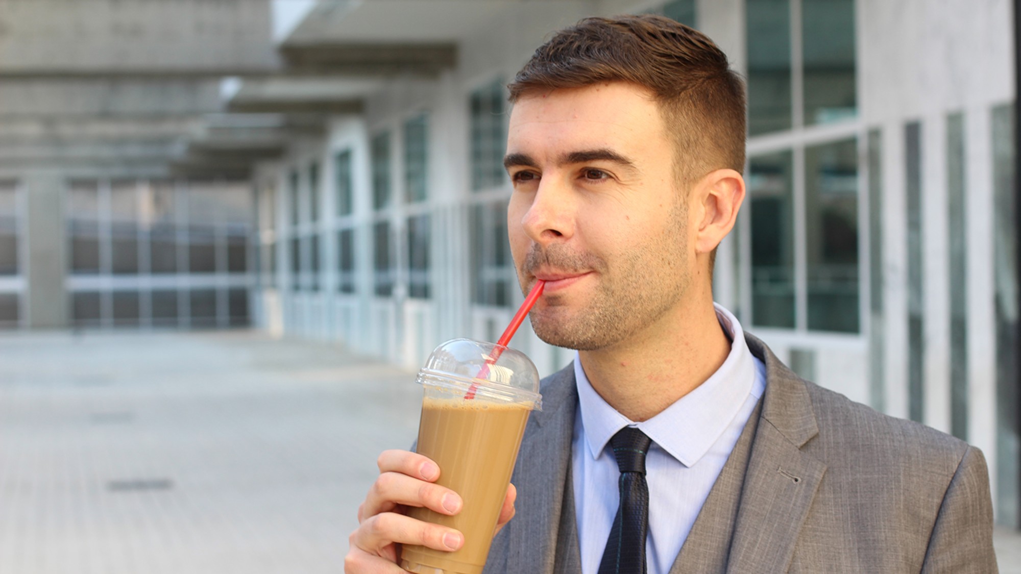 A stock photo of a man drinking iced coffee.