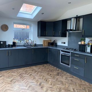 Overview of a kitchen with white walls, black cabinets, and parquet flooring