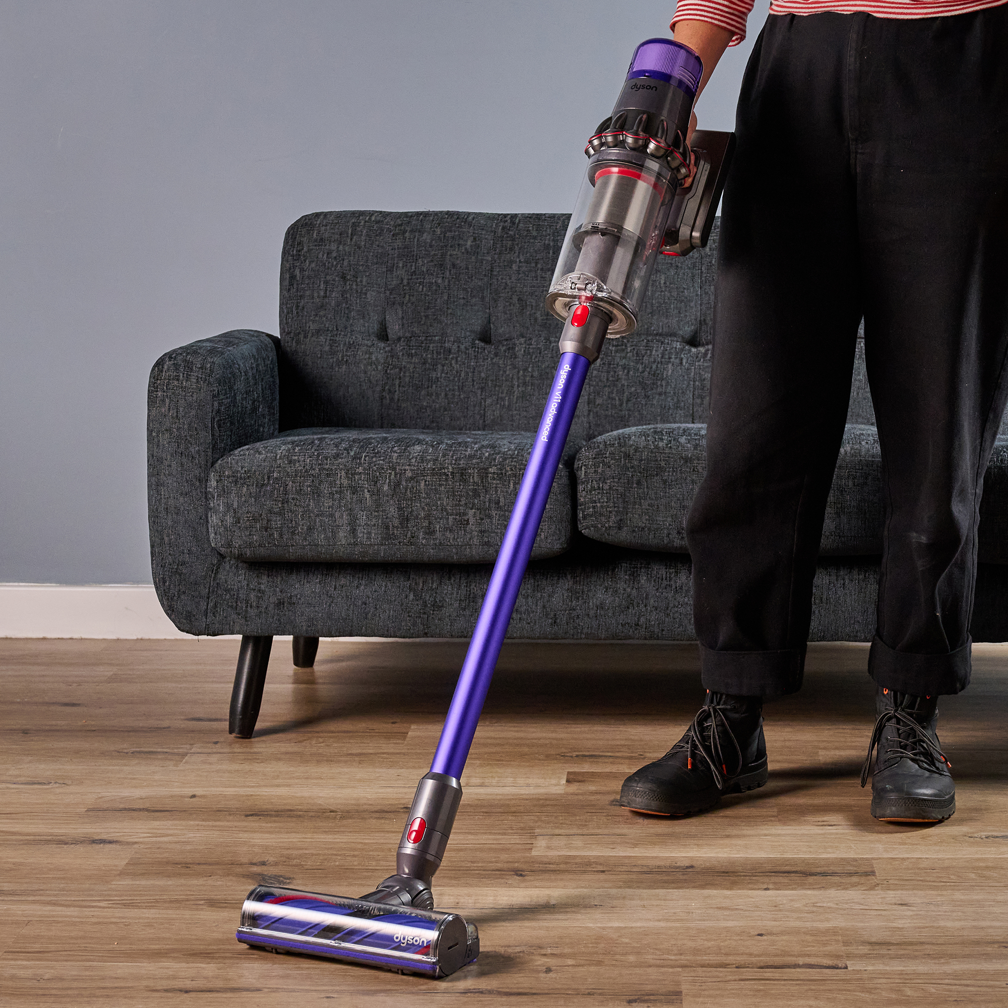 Writer holding Dyson V11 Advanced vacuum with sofa in the background