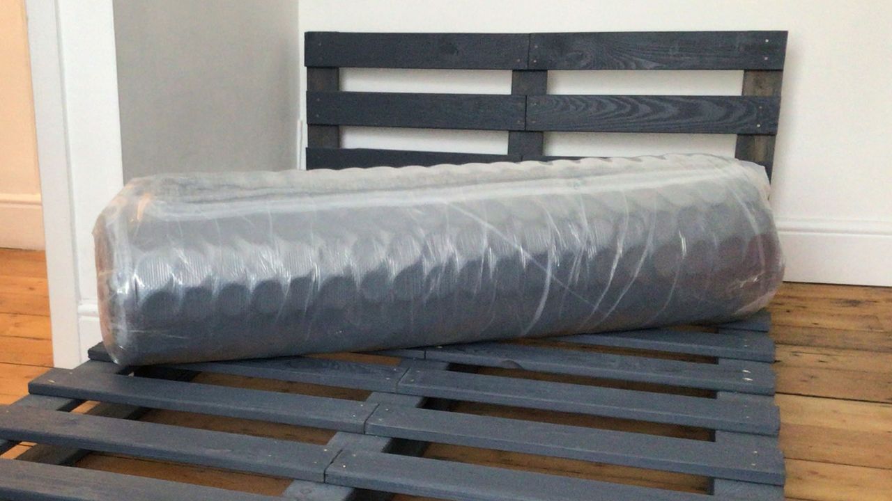 Origin Hybrid mattress vacuum packed and rolled on a bed frame