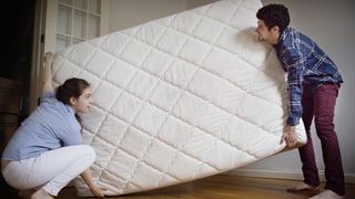 Two people carrying a mattress