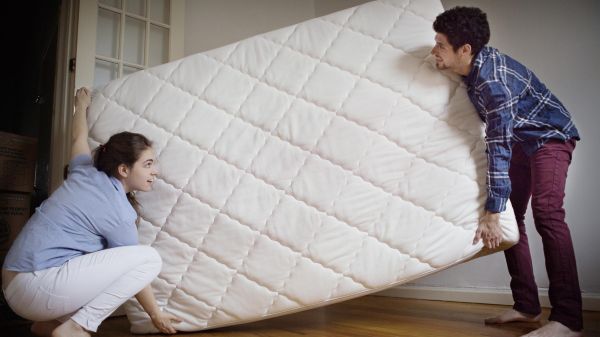 two people holding a mattress