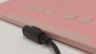 XP-Pen Deco 01 V2 cable plugged into the side of a pink drawing tablet