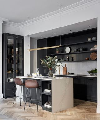 Grey kitchen ideas with white backsplash and worktop, herringbone flooring and a kitchen island with leather stools.