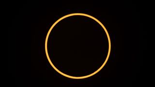 the annular solar eclipse appears as a thin ring of yellowy orange against a black background.