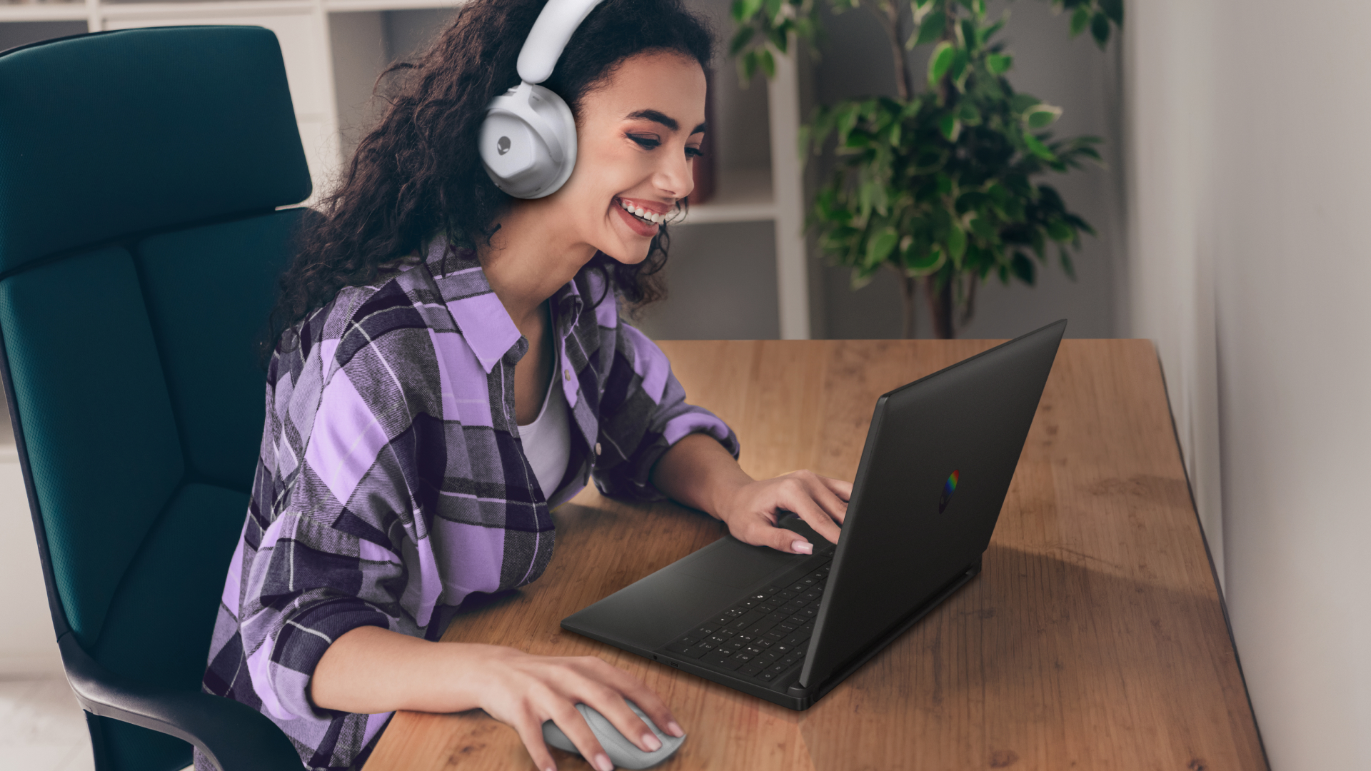 A woman smiles while playing a game on her Alienware 15 laptop