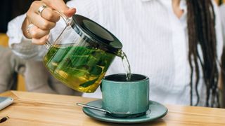 Woman pouring green tea onto mug