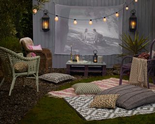 outdoor cinema setup with festoon lights and rugs on the floor