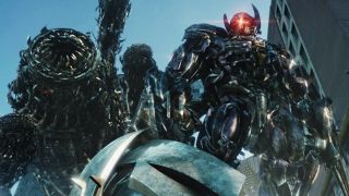 Still from the movie Trnsformers: Dark of the Moon (2011). Here we see an evil-looking black robot with horns and a shining red light erupting from his face. In the background there is a giant menacing mechanical worm with lots of 'teeth'.