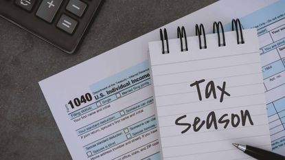 tax forms and a notebook with "tax season" written on a page