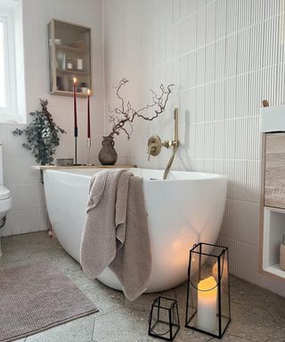 White bathtub with towels and a vase with branches