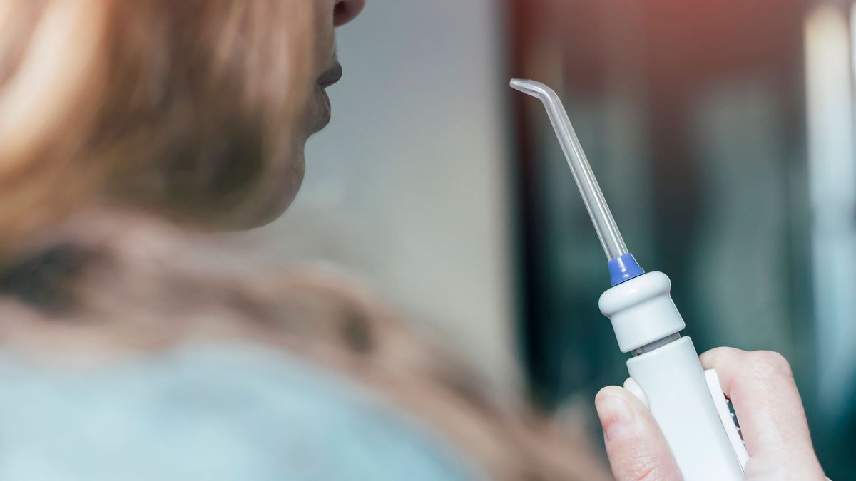 A woman holding a water flosser