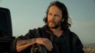 Taylor Kitsch in The Terminal List leaning his left arm against the back or a truck.