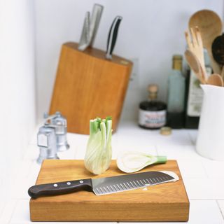 knife laid on a chopping board with some veg