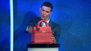 Mikey Day slices into a cake shaped like a purse in Is It Cake?