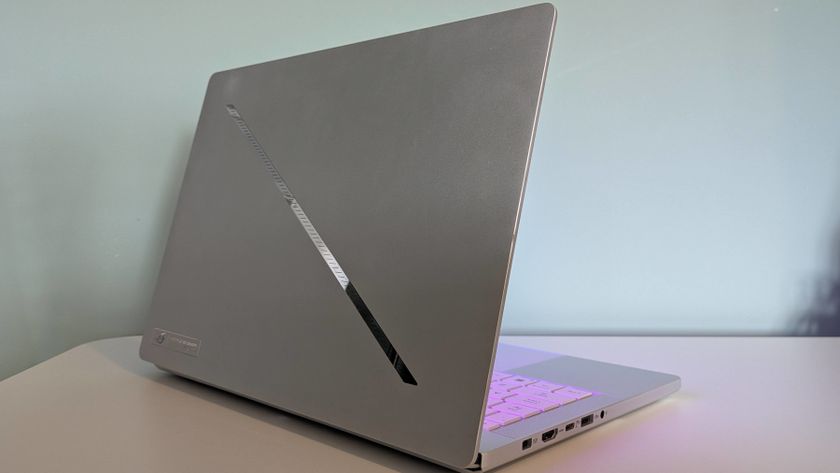 Back three-quarter view of Asus ROG Zephyrus G14 (2025) open on desk with green wall in background