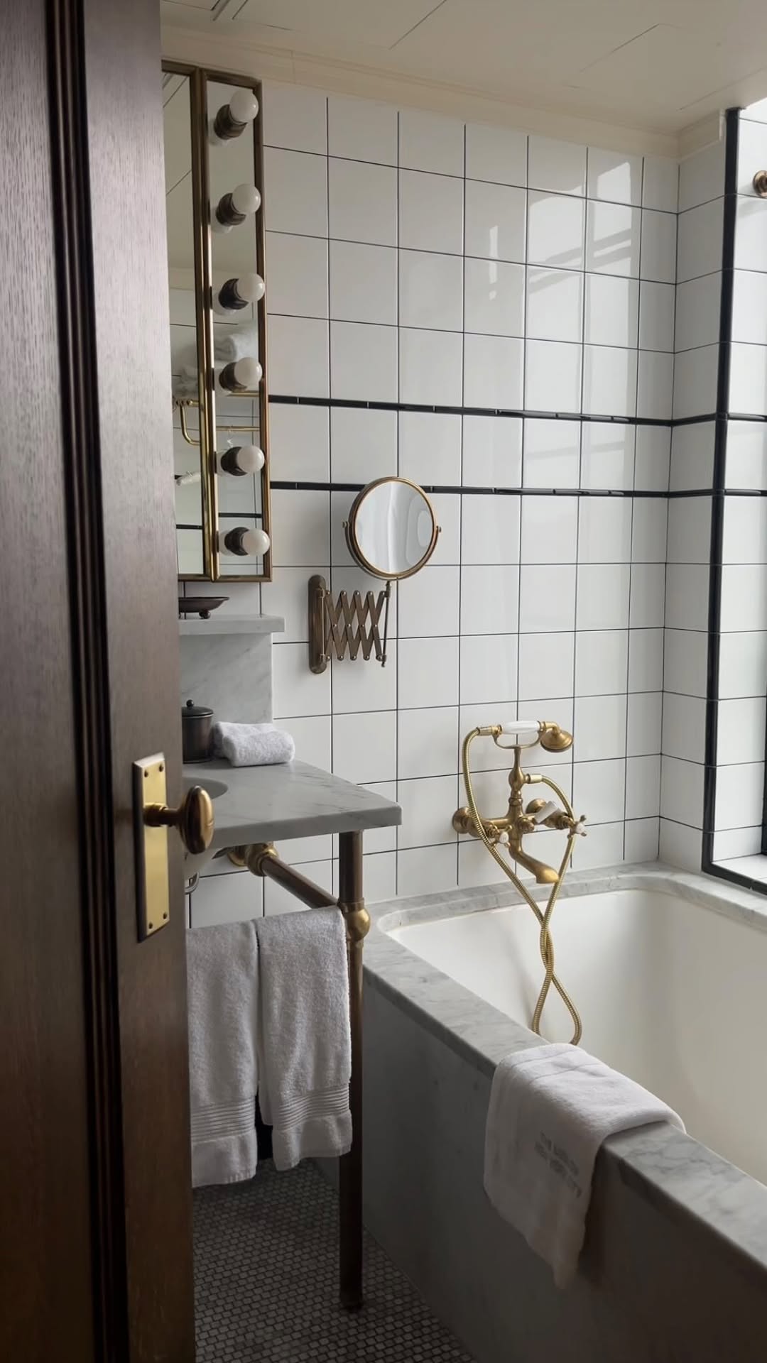 A bathroom with a marble bathtub and brass taps