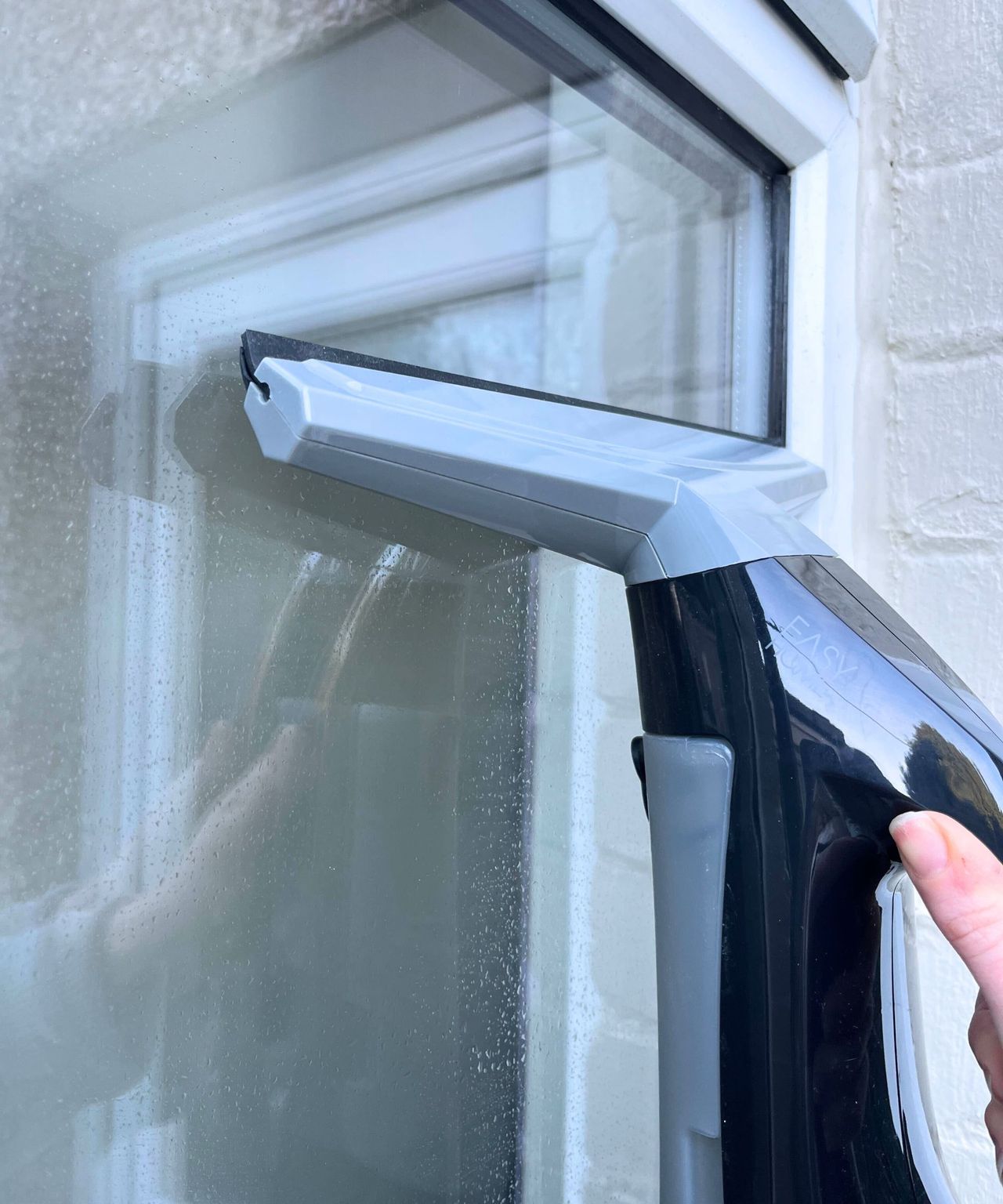 Using a gray window vacuum to suck up waster from a window outside