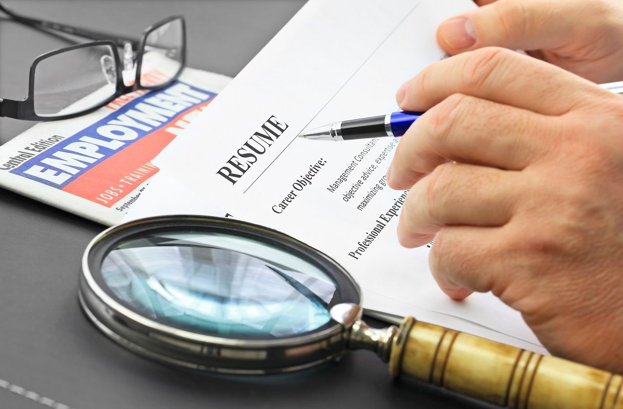 Businessman with pen analyzing resume at desk in the office