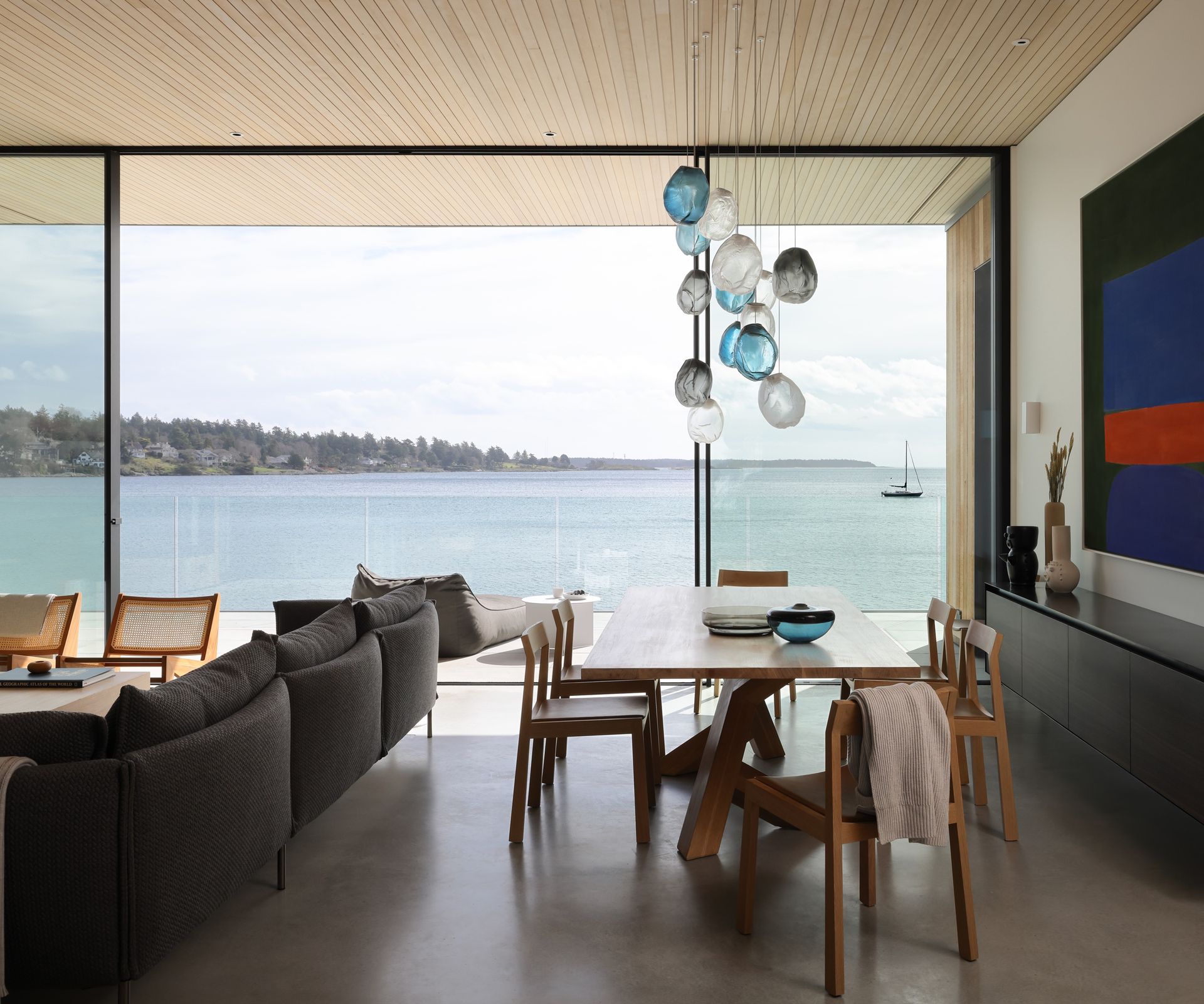 Open plan living and dining room with concrete floors and sea views