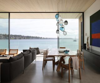 Open plan living and dining room with concrete floors and sea views