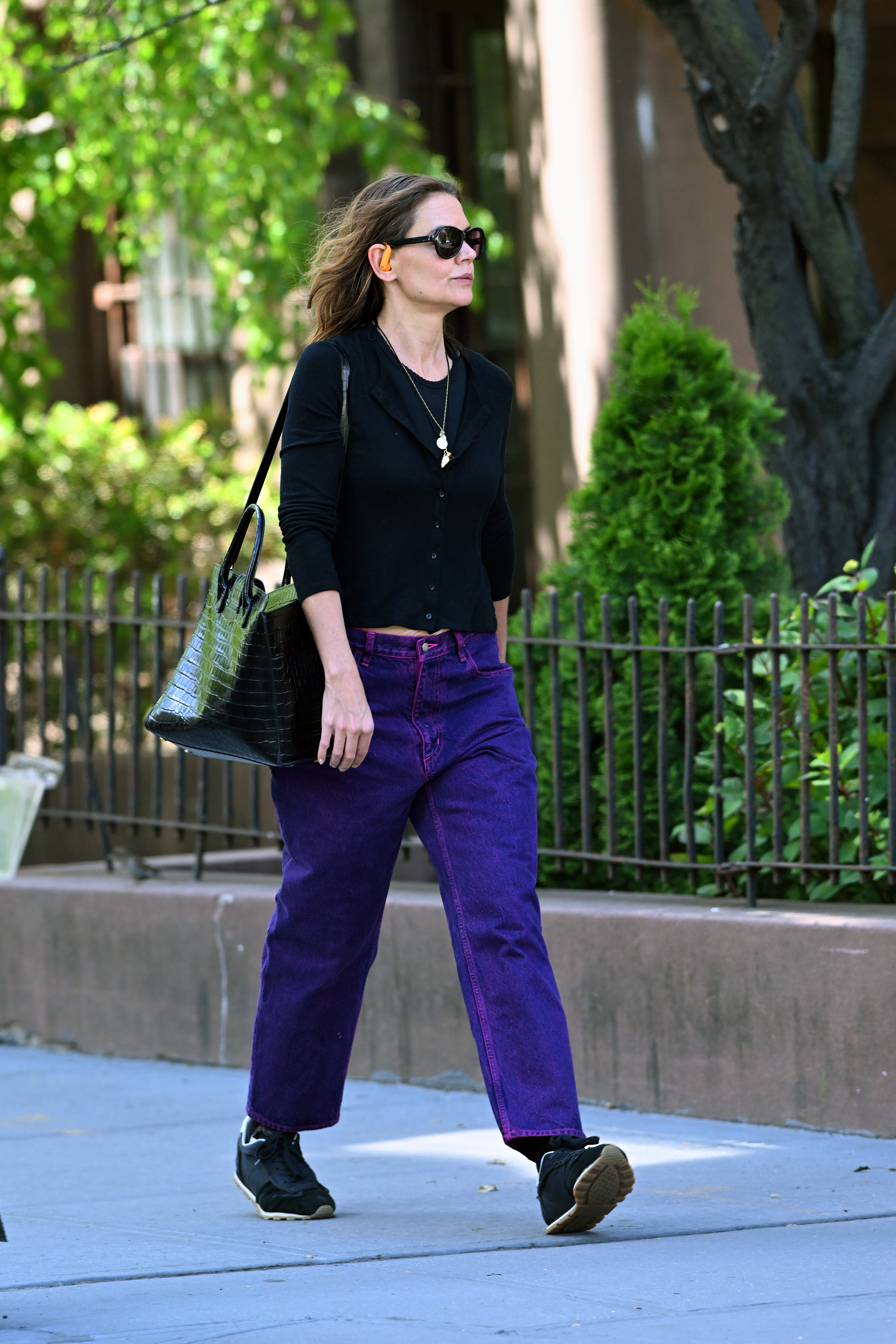 Katie Holmes wering a pendant necklace, a cardigan, jeans, and sneakers.