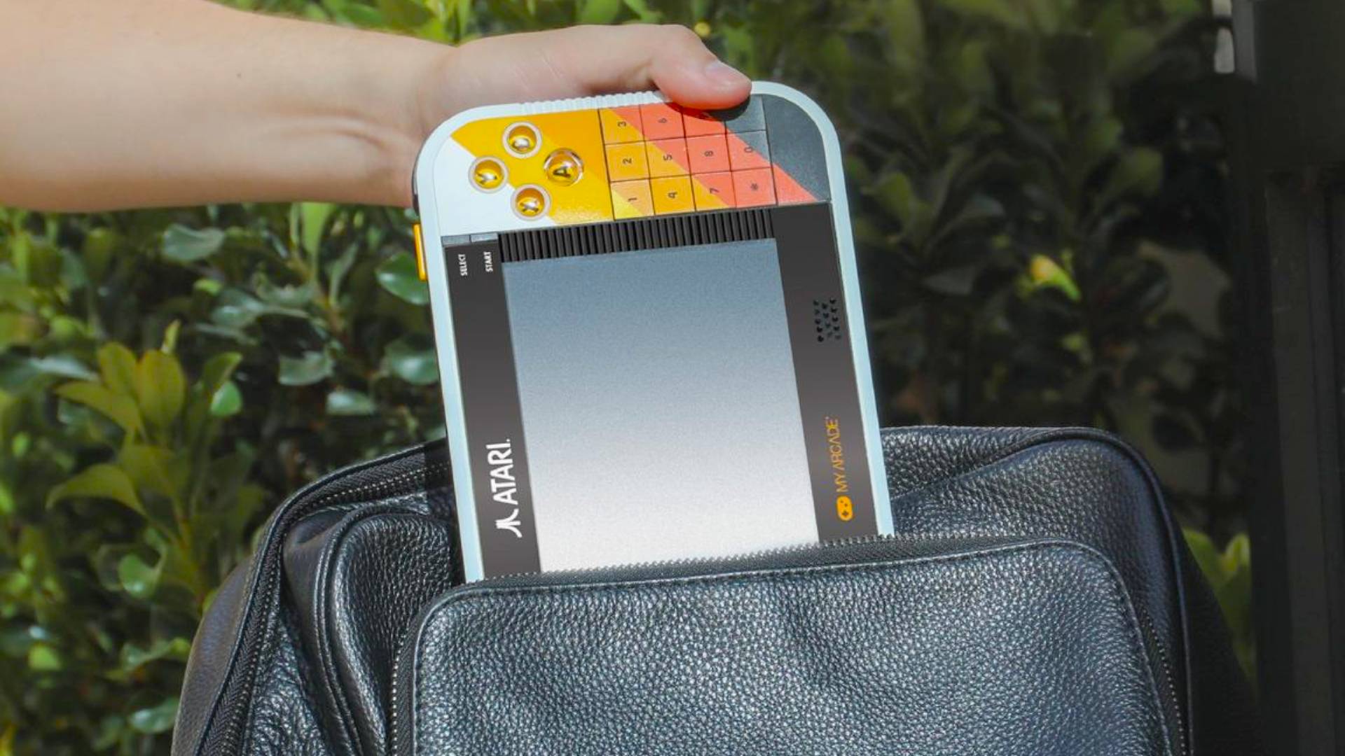 Hand pulling Atari Gamestation Go out of black bag.