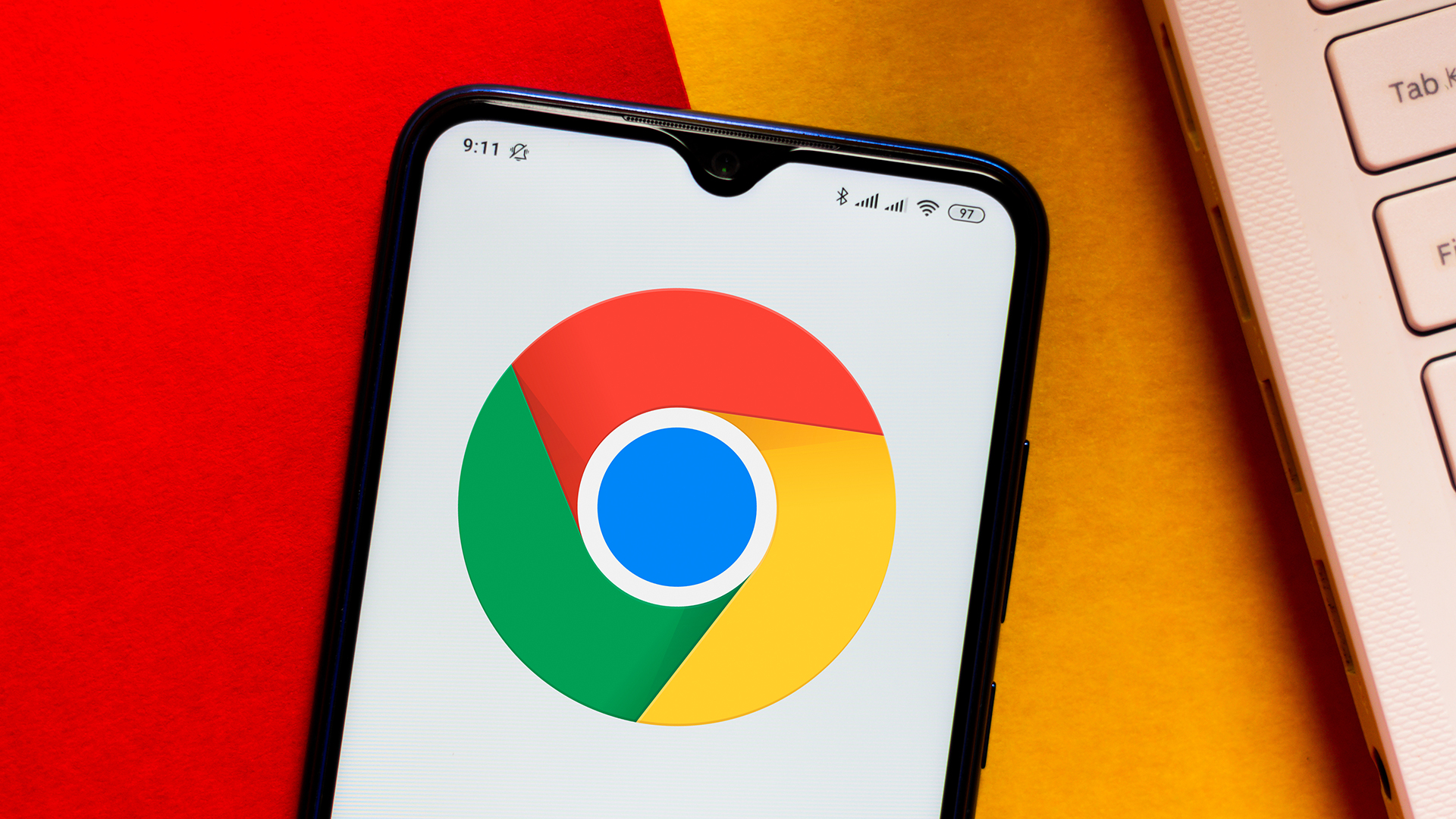 Google Chrome logotips, kas redzams Android viedtālrunī, kas atrodas uz oranžas un sarkanas virsmas