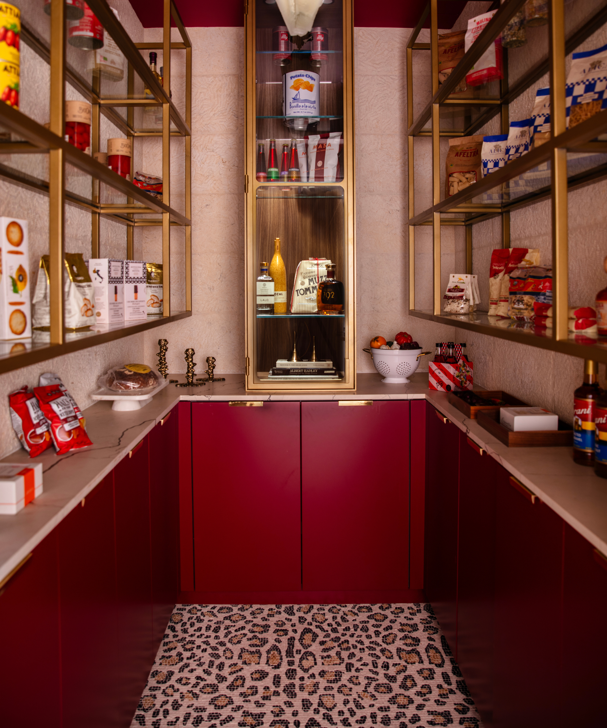 Bold cheetah-floored pantry space featuring bright red cabinetry with brass hardware and open shelving