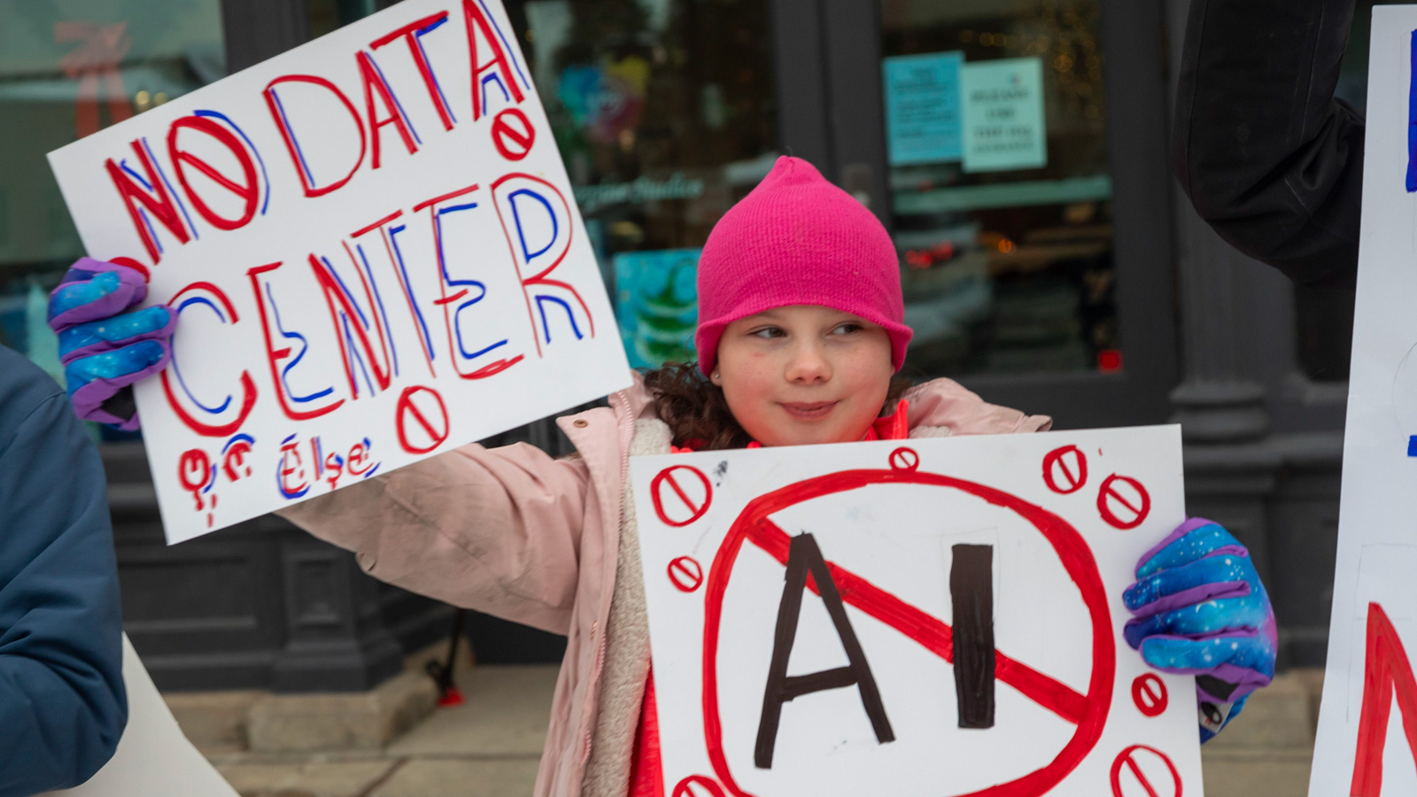 Young girl holding anti-ai signs at a protest.