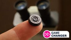 A finger holding a tiny camera lens for smartphones