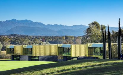 Exterior of the four villas featuring wood panelling, covered balconies, and mountains in the distance