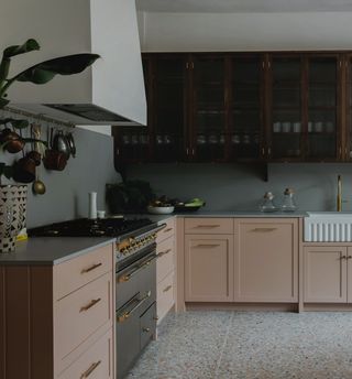 Dark wood and pink kitchen with terrazzo flooring