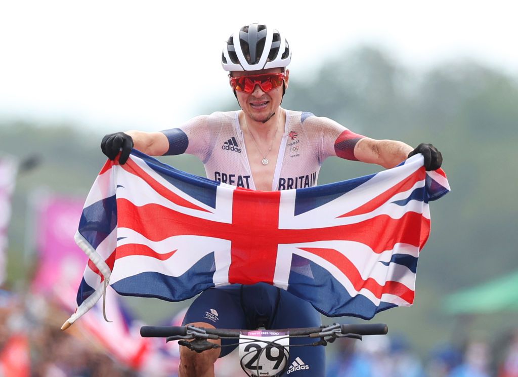 IZU JAPAN JULY 26 Thomas Pidcock of Team Great Britain celebrates winning the gold medal while holding the flag of his country during the Mens Crosscountry race on day three of the Tokyo 2020 Olympic Games at Izu Mountain Bike Course on July 26 2021 in Izu Shizuoka Japan Photo by Michael SteeleGetty Images