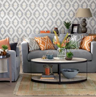 small grey living room with wallpaper and orange cushions