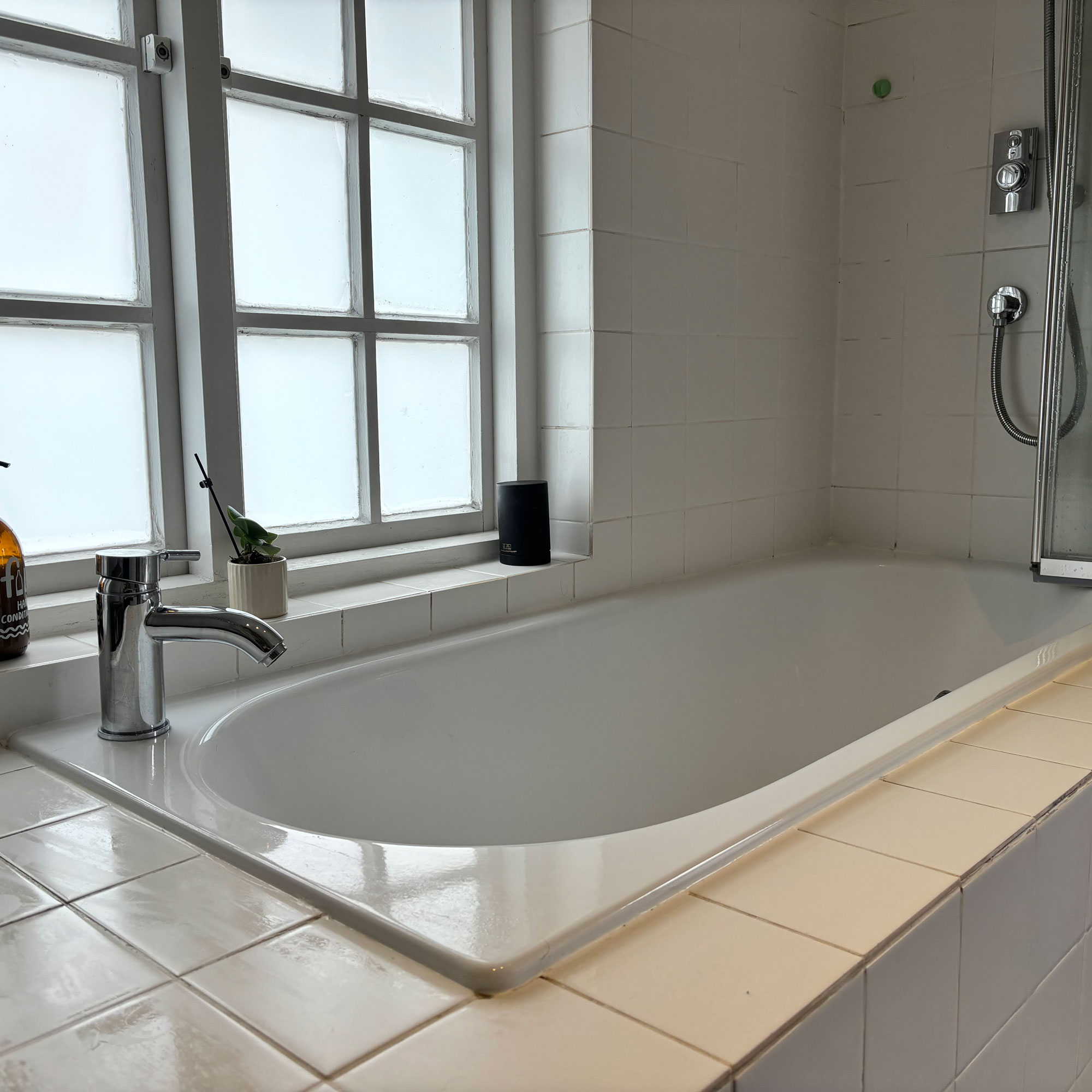 white bathroom with built-in bath and white tiles and chrome taps