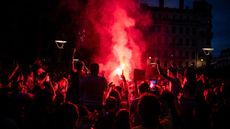 Left wing supporters light red flares as they celebrate during a rally after the announcement of the results of the second round of France's parliamentary elections