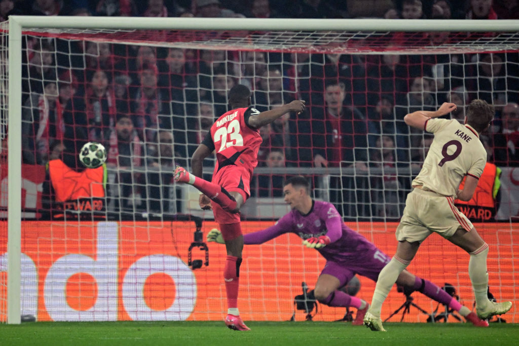 TOPSHOT - Bayern Munich's English forward #09 Harry Kane (R) scores the opening goal past Bayer Leverkusen's Czech goalkeeper #17 Matej Kovar (C) during the UEFA Champions League last 16, first-leg, football match FC Bayern Munich v Bayer 04 Leverkusen on March 5, 2025 in Munich, southern Germany. (Photo by Tobias SCHWARZ / AFP) (Photo by TOBIAS SCHWARZ/AFP via Getty Images)