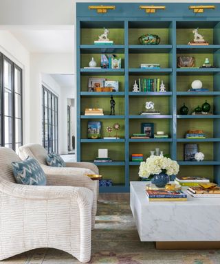 curved off white chairs, blue and green custom bookcase and marble table