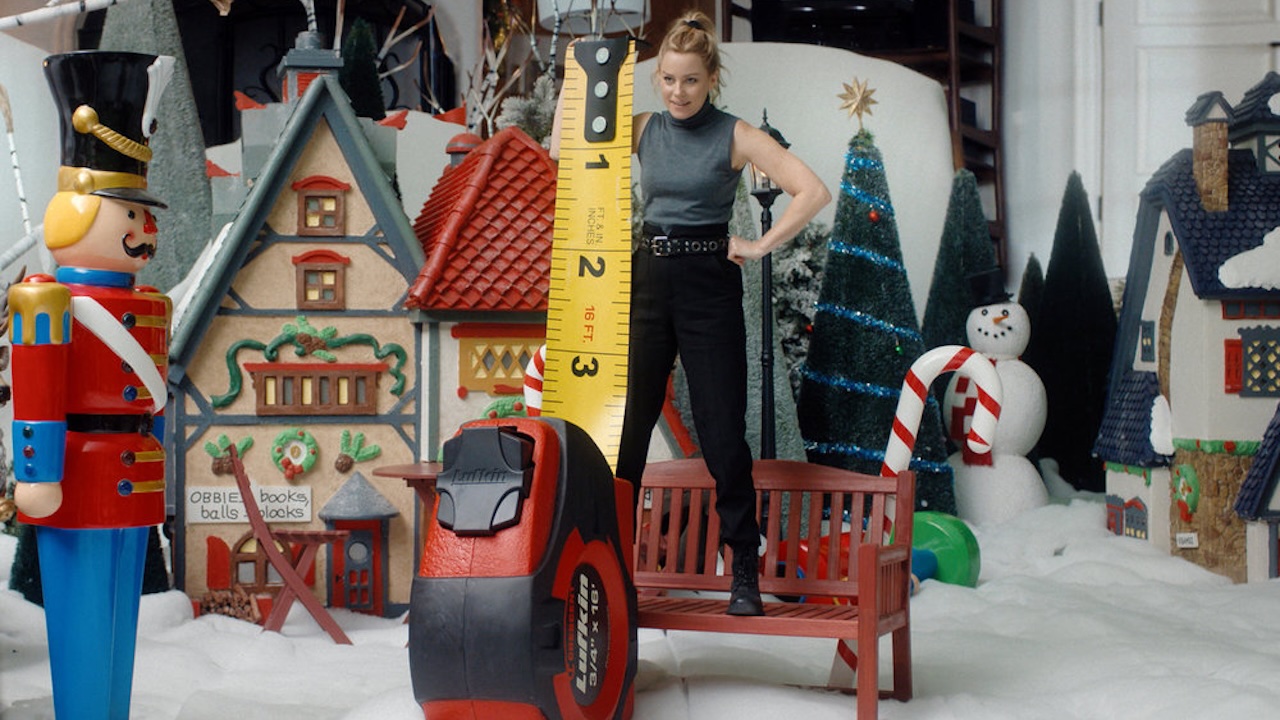 Elizabeth Banks measuring herself with a tape measurer in The Miniature Wife