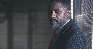 Luther actor Idris Elba standing against a window