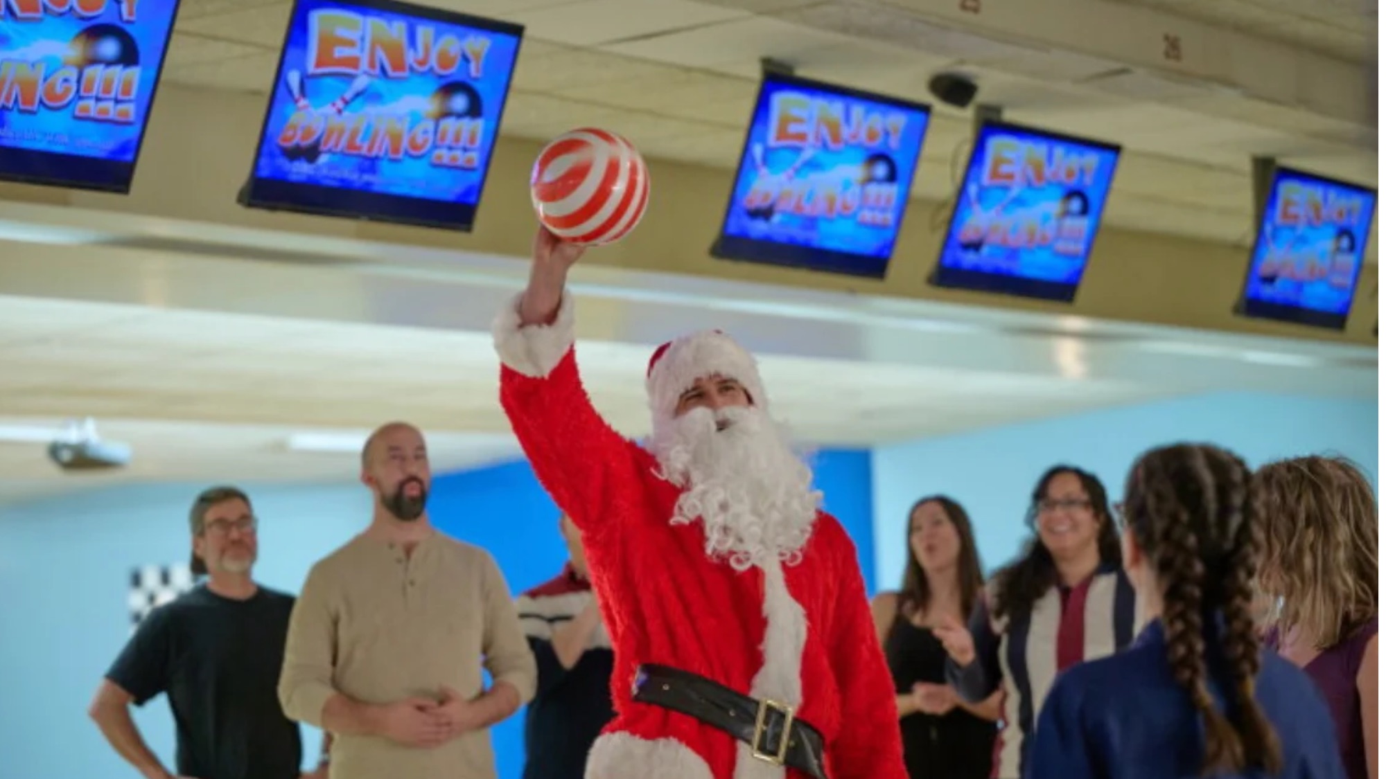 Franco Lo Presti dressed as Santa holding a candy cane striped bowling ball in the air in Winter Wonderlands