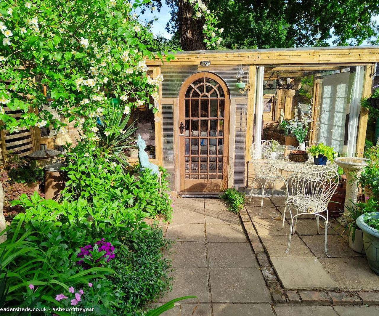 A shed with plastic surroundings and a wooden frame and surrounded by plants