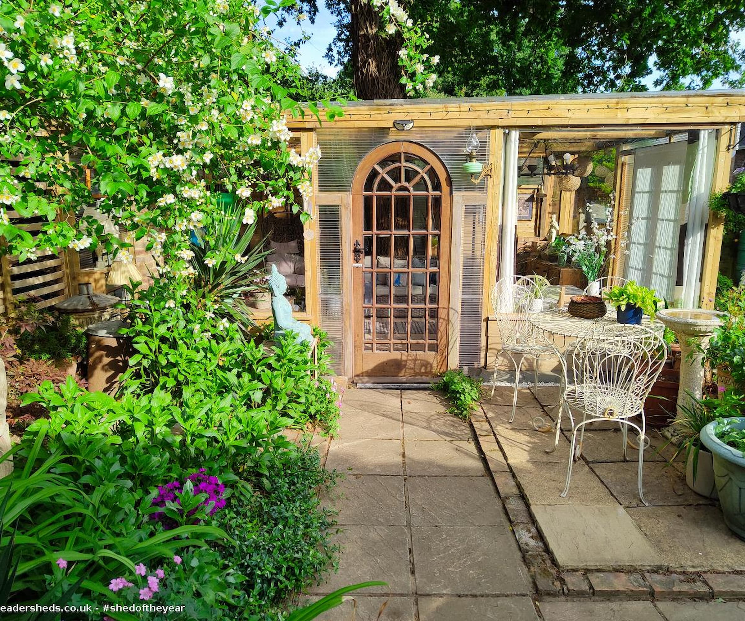 A shed with plastic surroundings and a wooden frame and surrounded by plants