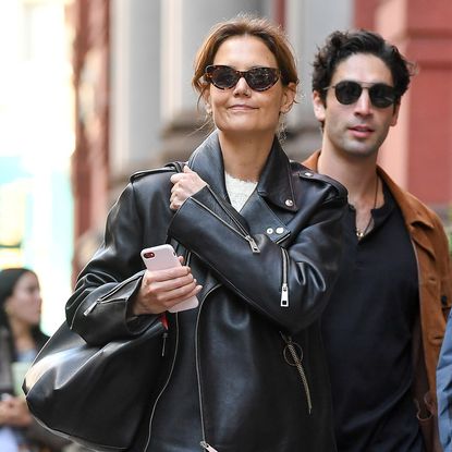 Katie Holmes walking Manhattan's Soho neighborhood wearing a leather moto jacket with her wardrobe staples