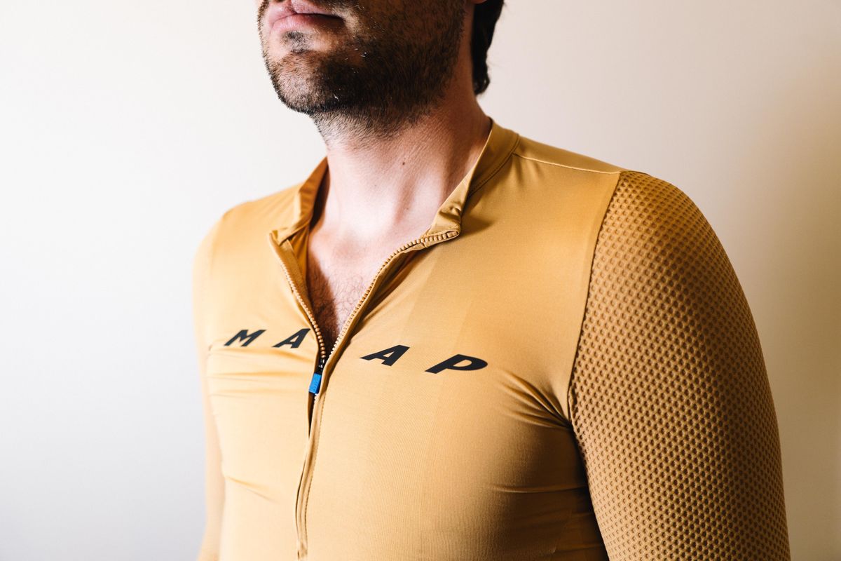 A white man in a tan jersey against a white wall